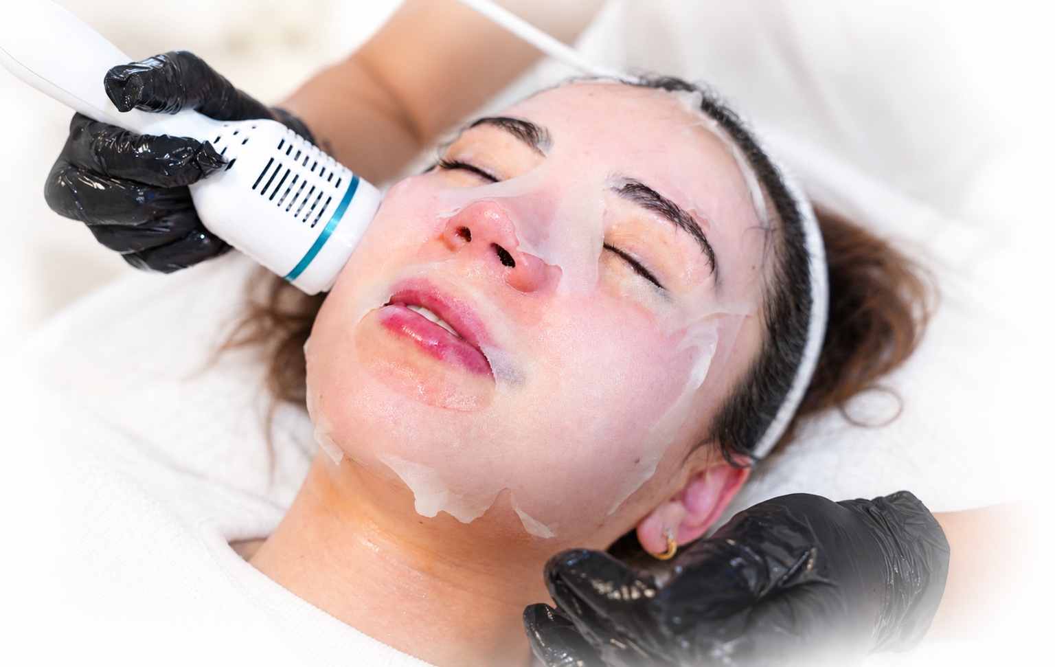 Facial treatment with a sheet mask and handheld skincare device